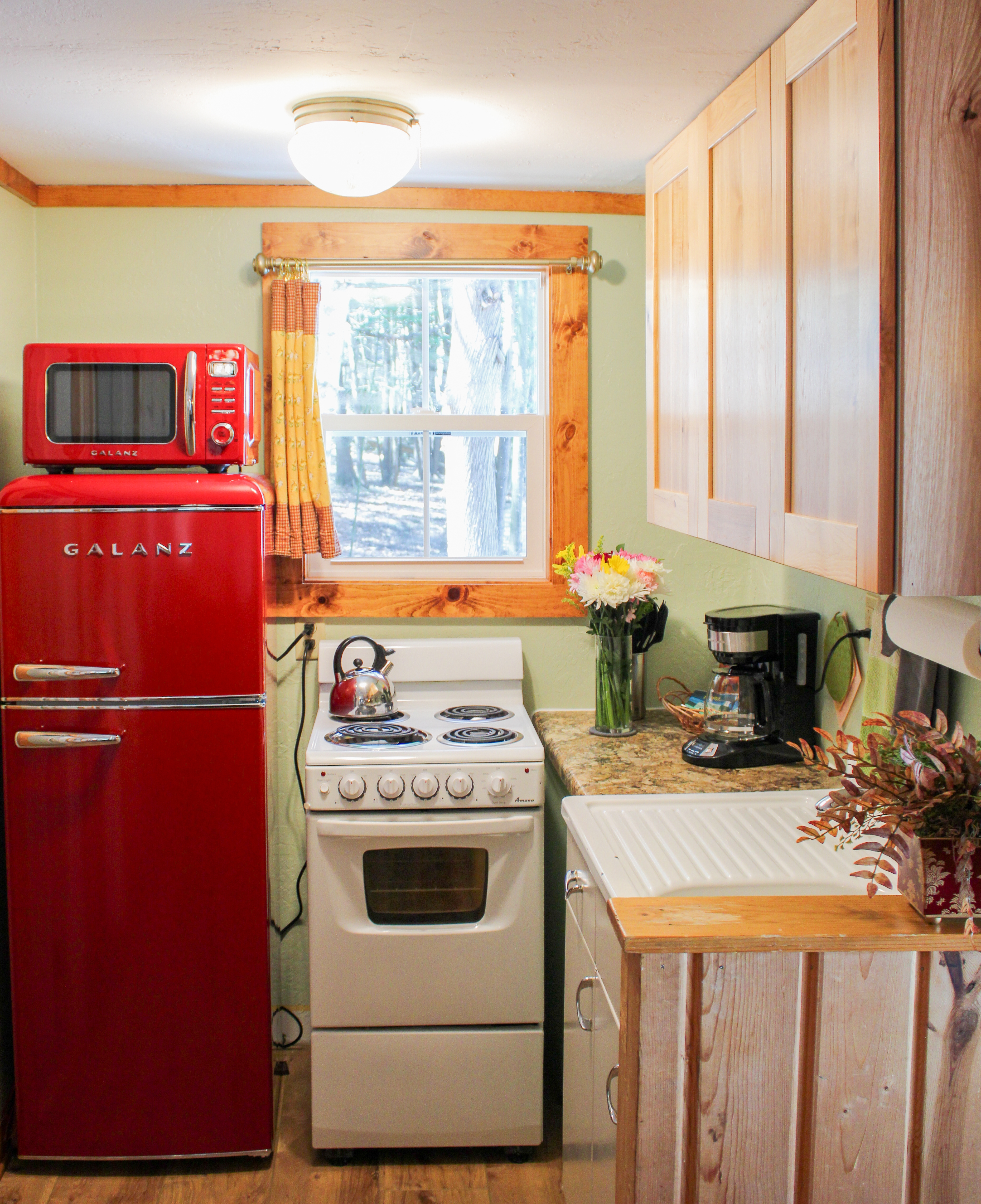 A warm and rustic kitchen and dining area with wood-paneled walls, a small dining table with wine, and a compact kitchen setup.