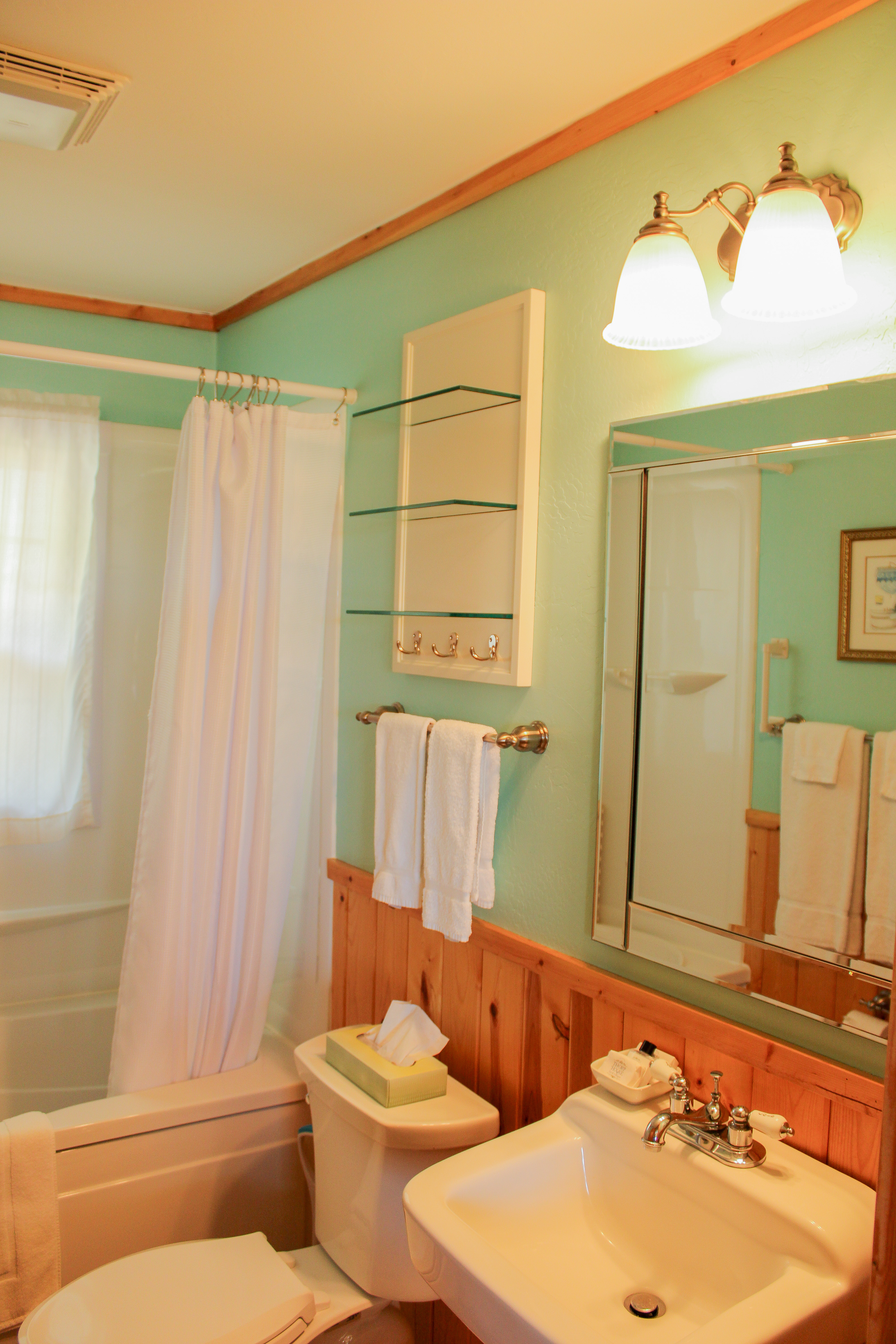 A vibrant green bathroom with a white sink, toilet, bathtub with shower, and decorative accents.