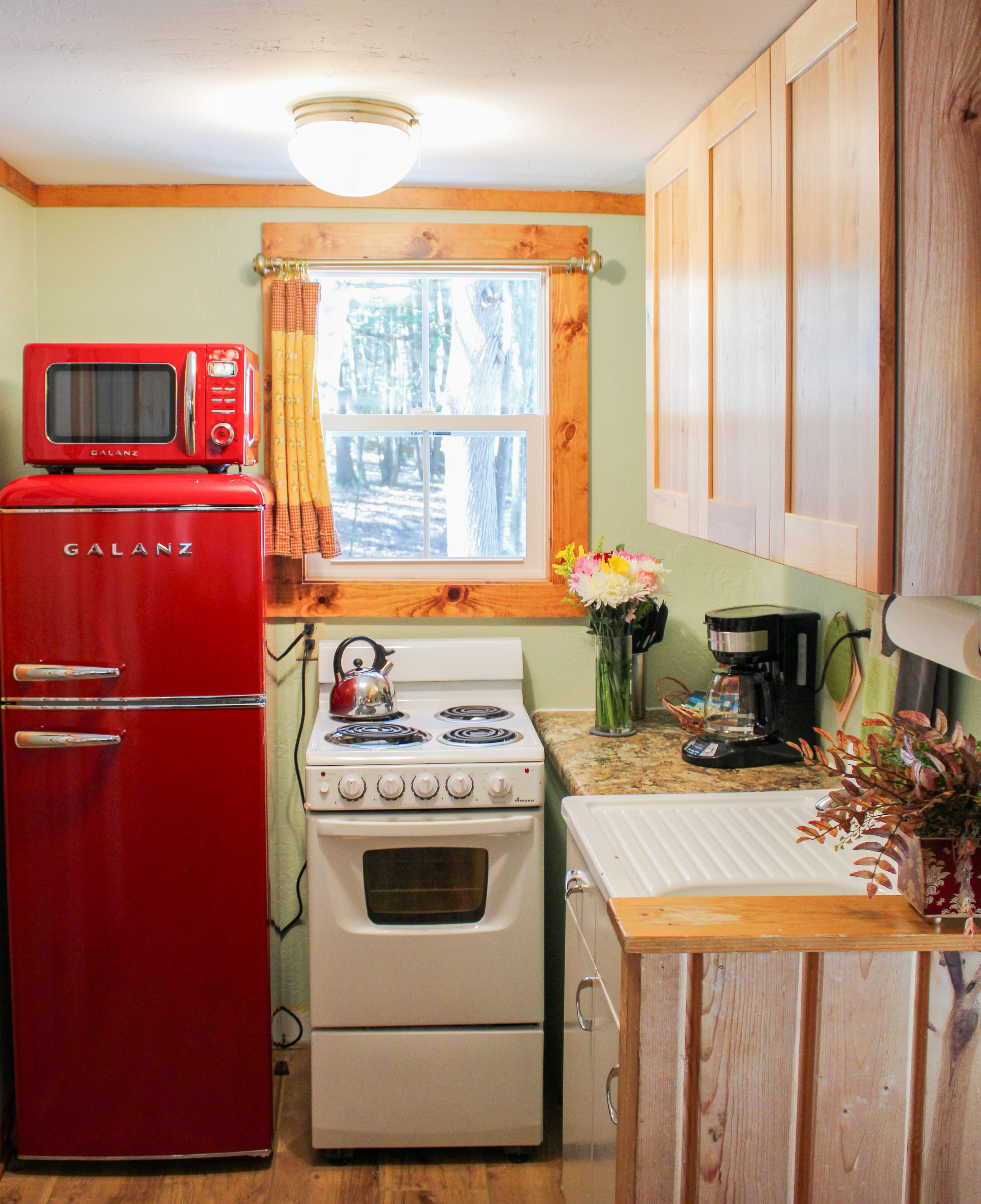 A warm and rustic kitchen and dining area with wood-paneled walls, a small dining table with wine, and a compact kitchen setup.