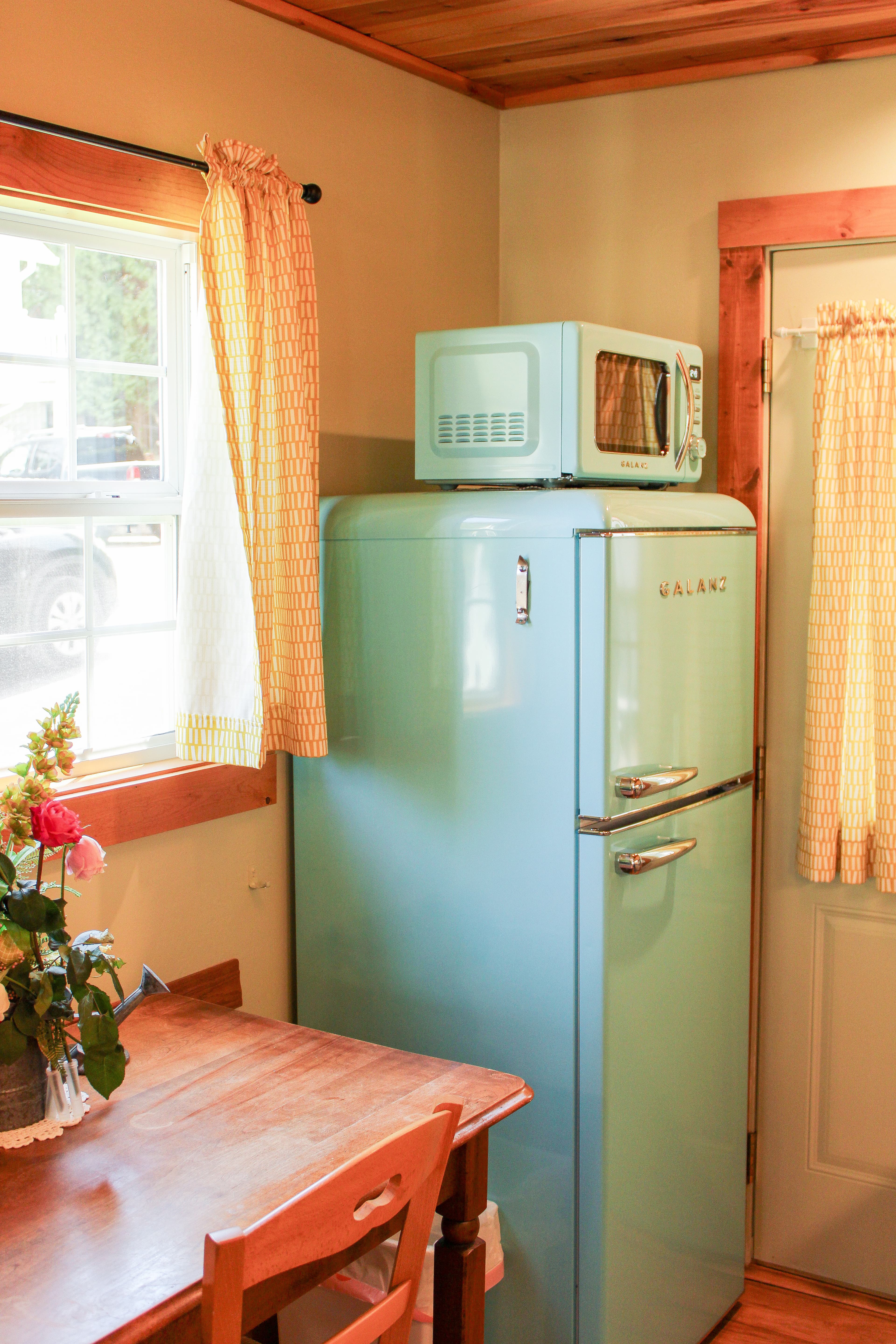 A kitchen with retro refrigerator and dining table.