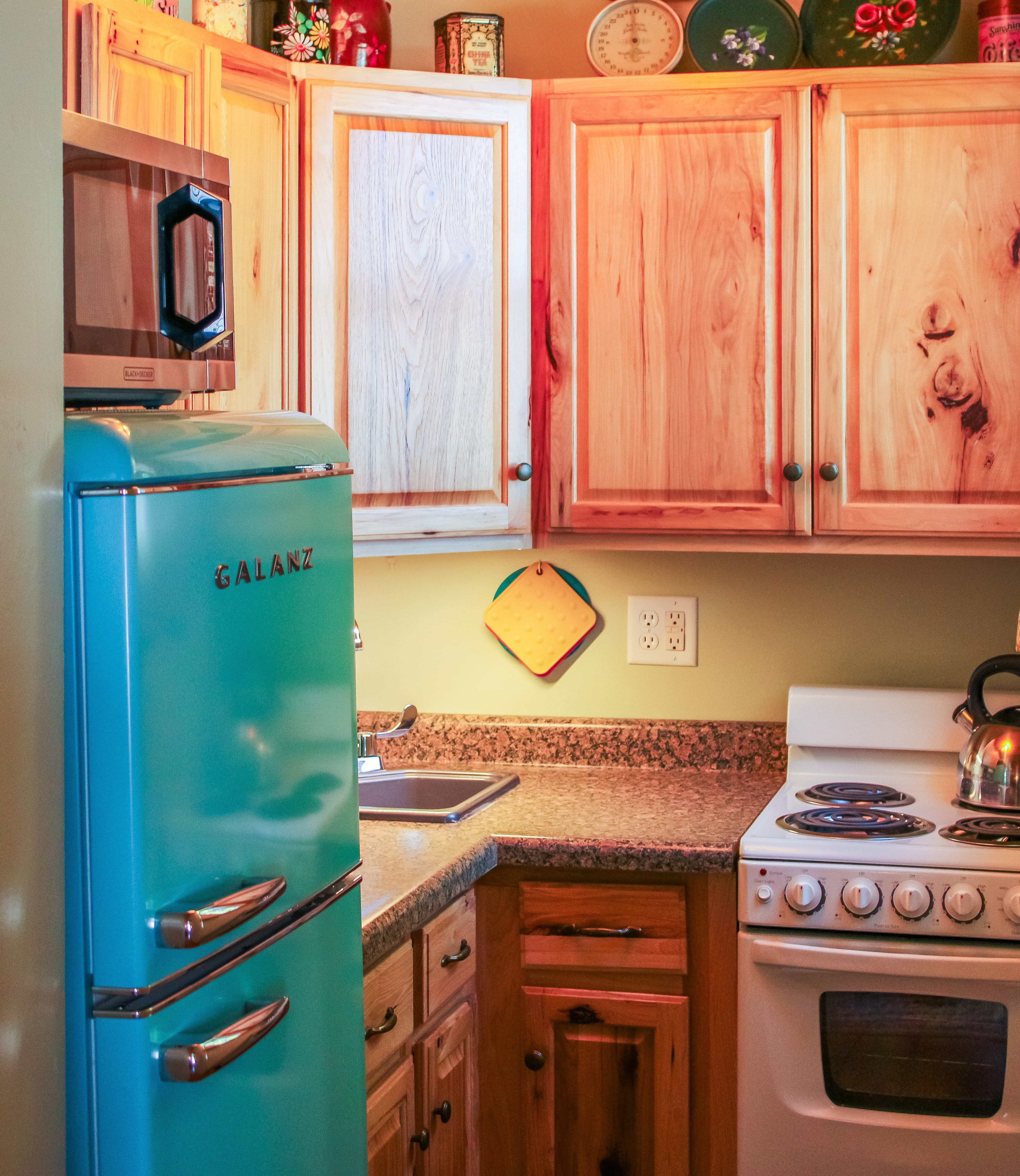 A functional kitchen with a blue retro refrigerator, countertops, white stove, and wood cabinets