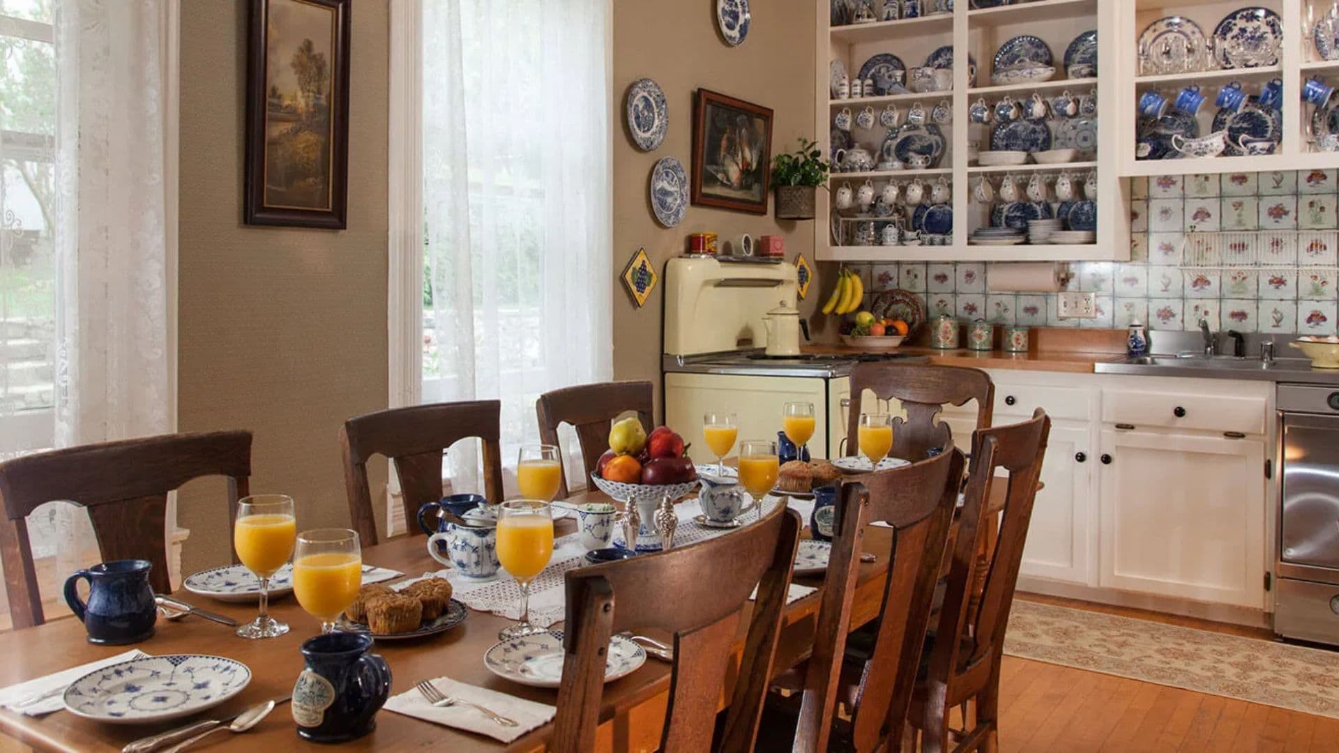 A cozy dining room set for breakfast with orange juice, muffins, and fruit.