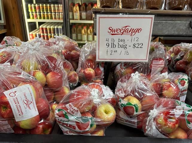 Bags of Sweetango apples are displayed with price signs for 4 lb and 9 lb bags.