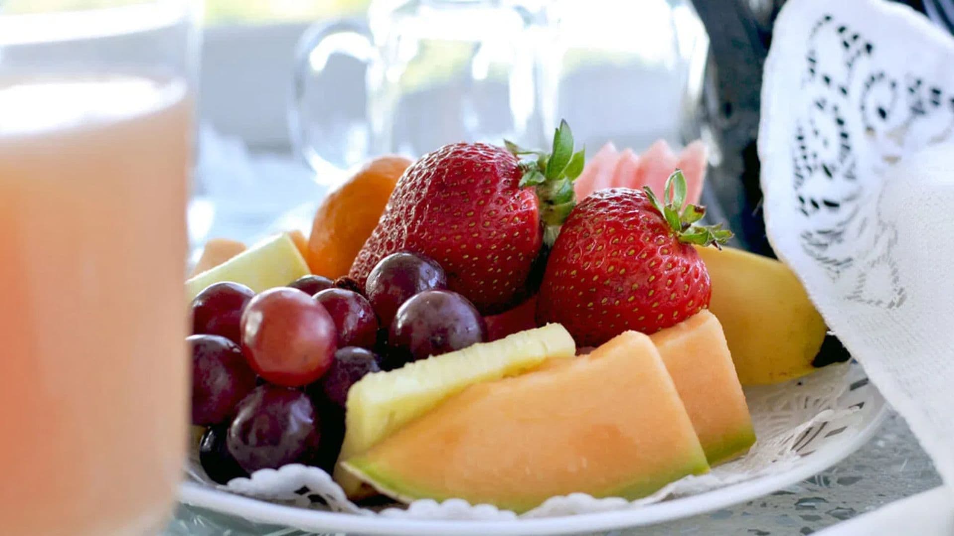 A colorful assortment of fresh fruits including strawberries, grapes, and melon on a delicate plate.