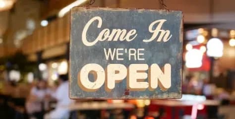 A vintage-style hanging sign that reads "Come In, We're Open."
