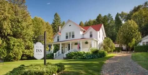 A charming white inn with a red roof surrounded by lush greenery.