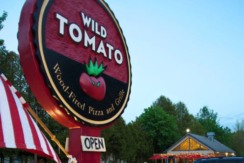 Sign for Wild Tomato, a wood-fired pizza restaurant, with "OPEN" displayed.