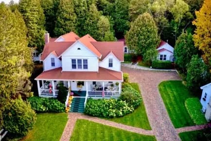 Aerial view of a white house with a red roof surrounded by greenery and a landscaped yard. Aerial view of a white house with a red roof surrounded by greenery and a landscaped yard.